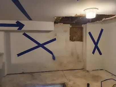 Tape on a wall marking high moisture readings below a ceiling that has been opened