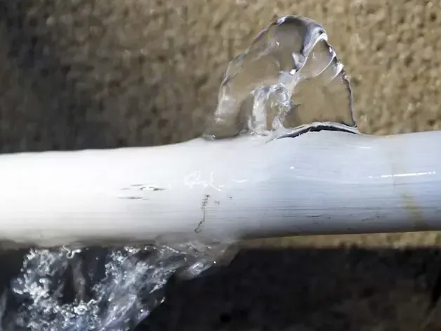 A split plastic supply pipe spraying water