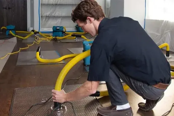 A yellow extraction hose pulling water off a soaked hardwood floor